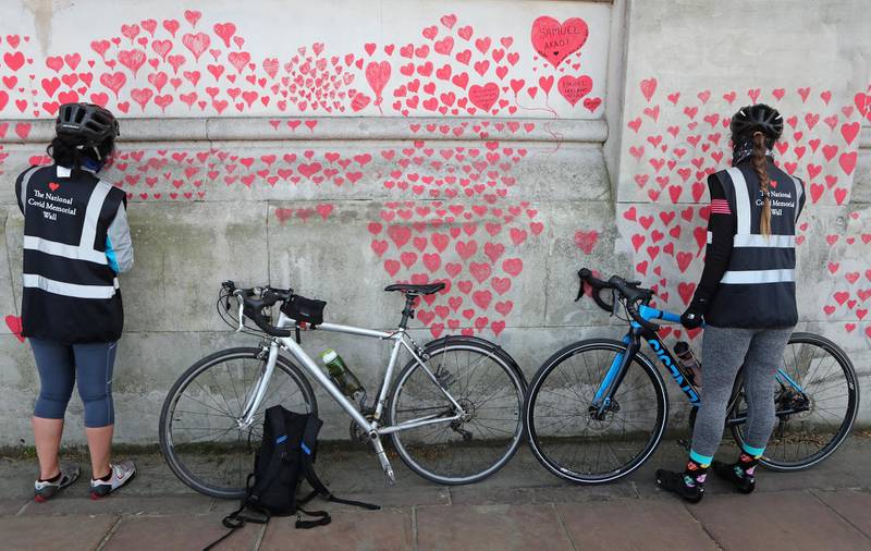 Women draw hearts on the National Covid Memorial Wall on the south bank of the Thames in London. AP Photo