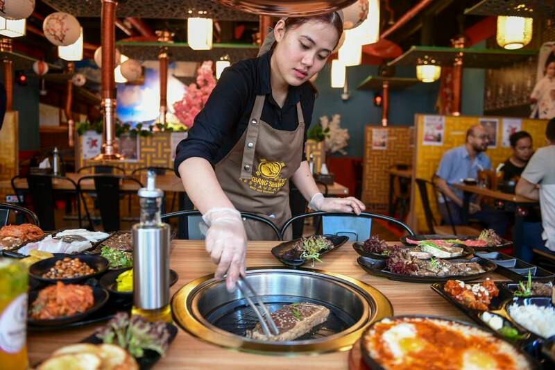 Sushmita, a server, grills a fresh striploin for Korean BBQ at Mukbang Shows Restaurant