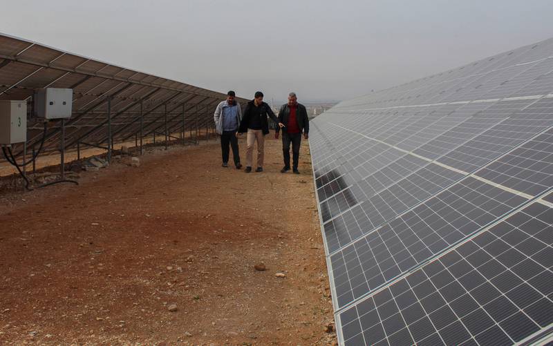 Businessman Baraa Sheira takes a tour with workers at his solar farm, in Hama.