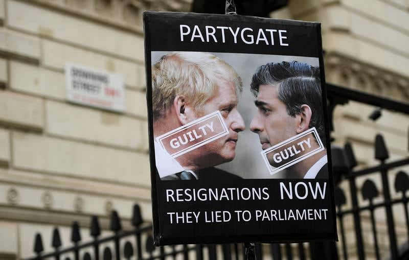 A protester holds up a placard of British Prime Minister Boris Johnson and Chancellor Rishi Sunak outside Downing Street. EPA