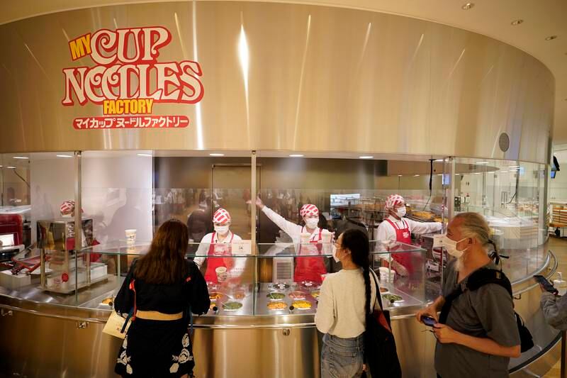 Staff members prepare instant noodles for visitors at the My Cup Noodles Factory at the CupNoodles Museum. EPA