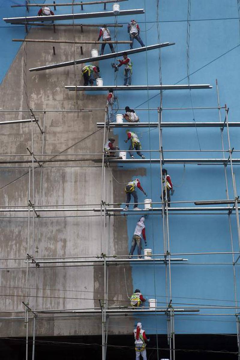 Workers paint the building of a new branch of a SM mall in Paranaque, metro Manila. Erik De Castro / AP Photo
