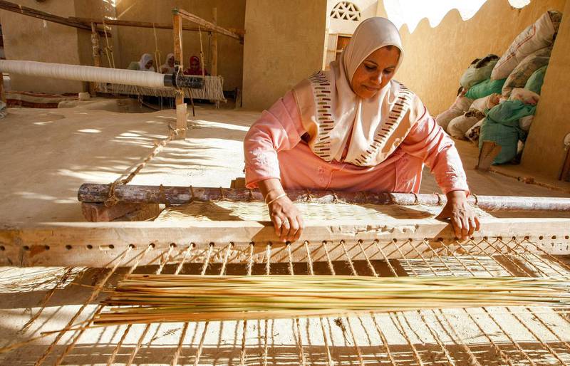 A Bedouin woman threads reeds as she weaves a rug at the Al Hayah community co-operative in the El Farafra Oasis, southwest of Cairo. AFP