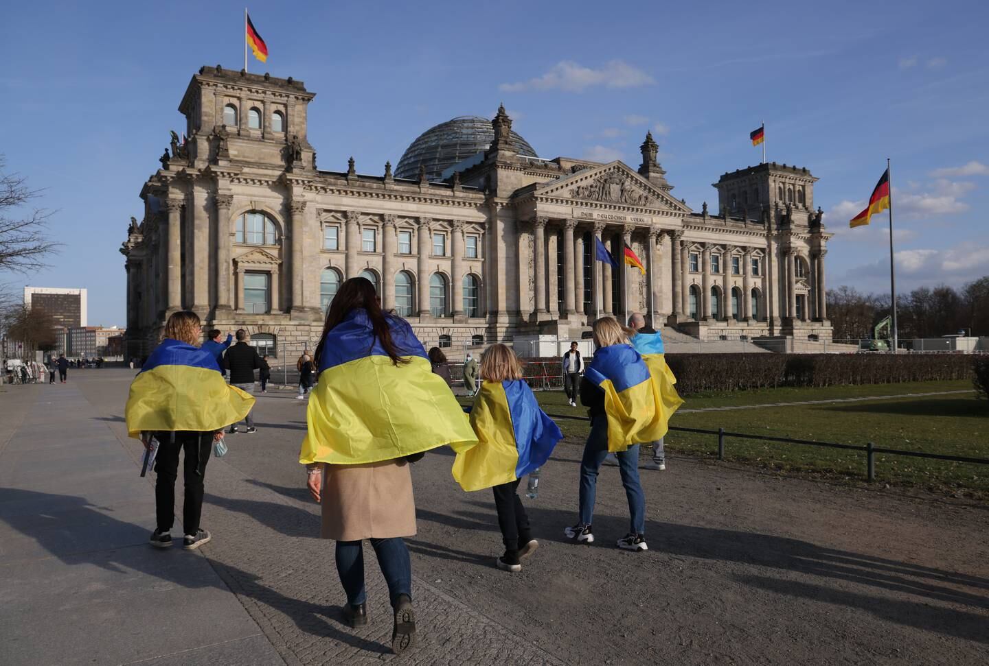 Protesters draped in Ukrainian flags walk past the Reichstag, the seat of Germany's Parliament in Berlin. Getty 
