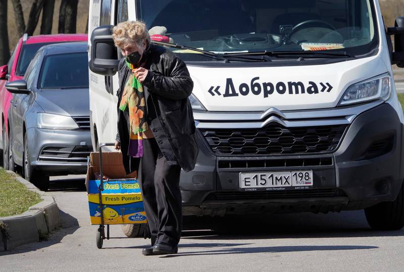 Galina Yakovleva pulls a cart with charity food and goods from her minivan, which has the word 'kindness' painted on the front. AP Photo