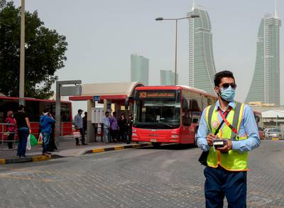 A bus conductor wearing a surgical mask stands in front of a bus station in the Bahraini capital Manama.  AFP
