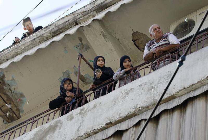 Residents stand on the balcony of their home near the scene of twin suicide bombings in Beirut's Burj Al Barajneh neighbourhood on November 13, 2015. Bilal Hussein, File/AP Photo