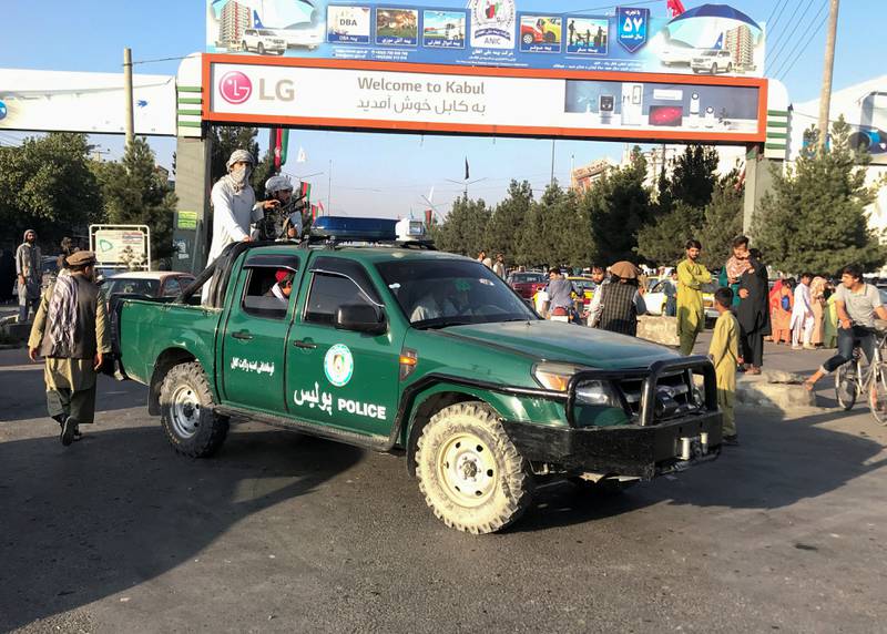 Taliban fighters on a police vehicle outside Hamid Karzai International Airport in Kabul, Afghanistan.