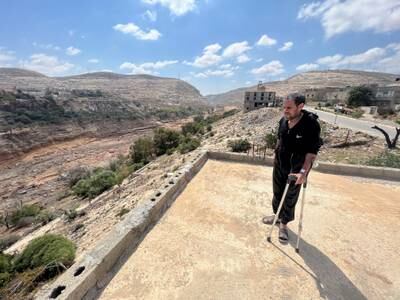 Abdulkarim Ben Ali uses crutches as he walks on the roof of his sister's damaged house. Reuters
