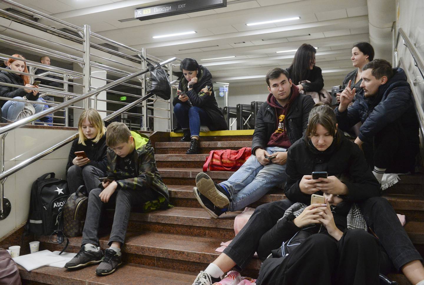 People check their phones as they shelter inside a metro station after shelling in Kyiv during the missile strikes. EPA