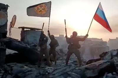 Wagner group troops wave the Russian flag over Bakhmut after claiming to have taken the entire ruined city. AFP