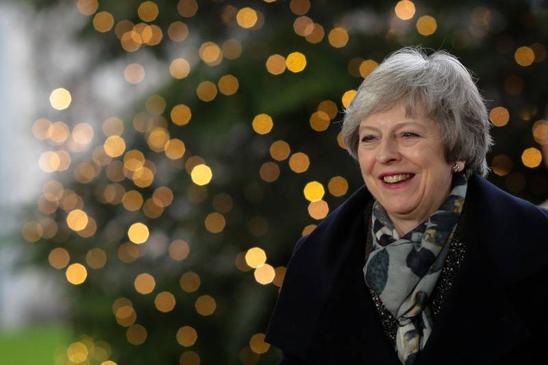 In this Dec. 11, 2018 photo British Prime Minister Theresa May smiles in front of a Christmas tree when arriving for a meeting with German Chancellor Angela Merkel at the chancellery in Berlin. (AP Photo/Markus Schreiber)