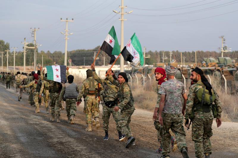Turkey-backed Syrian rebel fighters hold the Syrian opposition flag as they walk together in the border town of Akcakale in Sanliurfa province, Turkey. Reuters