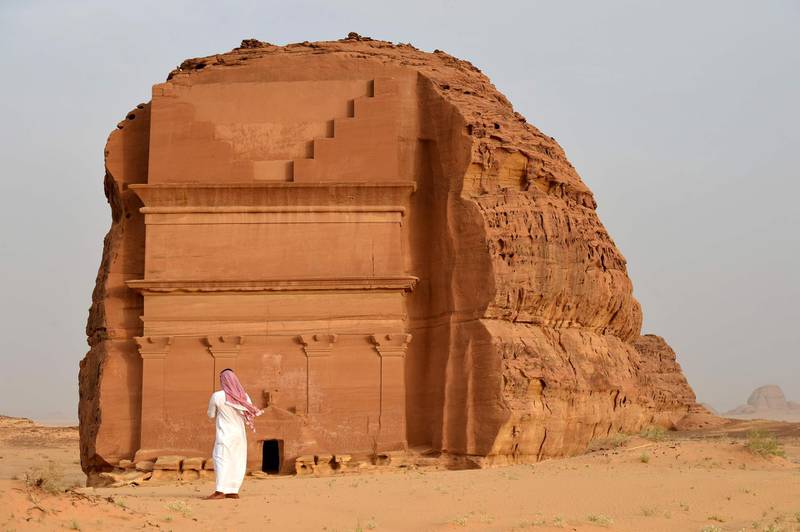 (FILES) This file photo taken on March 31, 2018 shows a man standing outside of the Qasr al-Farid tomb (The Lonely Castle) carved into rose-coloured sandstone in Madain Saleh, a UNESCO World Heritage site, near Saudi Arabia's northwestern town of al-Ula. Citizens from 49 countries are now eligible for tourist visas online or on arrival to Saudi Arabia, thanks to a landmark decision enacted last month, relaxing rules that had largely restricted visits to business travellers and Muslim pilgrims, with the authorities banking on large cities like the capital Riyadh and the western Red Sea port of Jeddah through large-scale investments, including in entertainment.
 / AFP / FAYEZ NURELDINE

