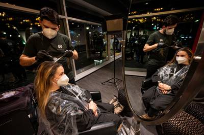 The first customer of Shan Rahimkhan's barbershop gets her hair cut and colored after the reopening in Berlin. AP Photo