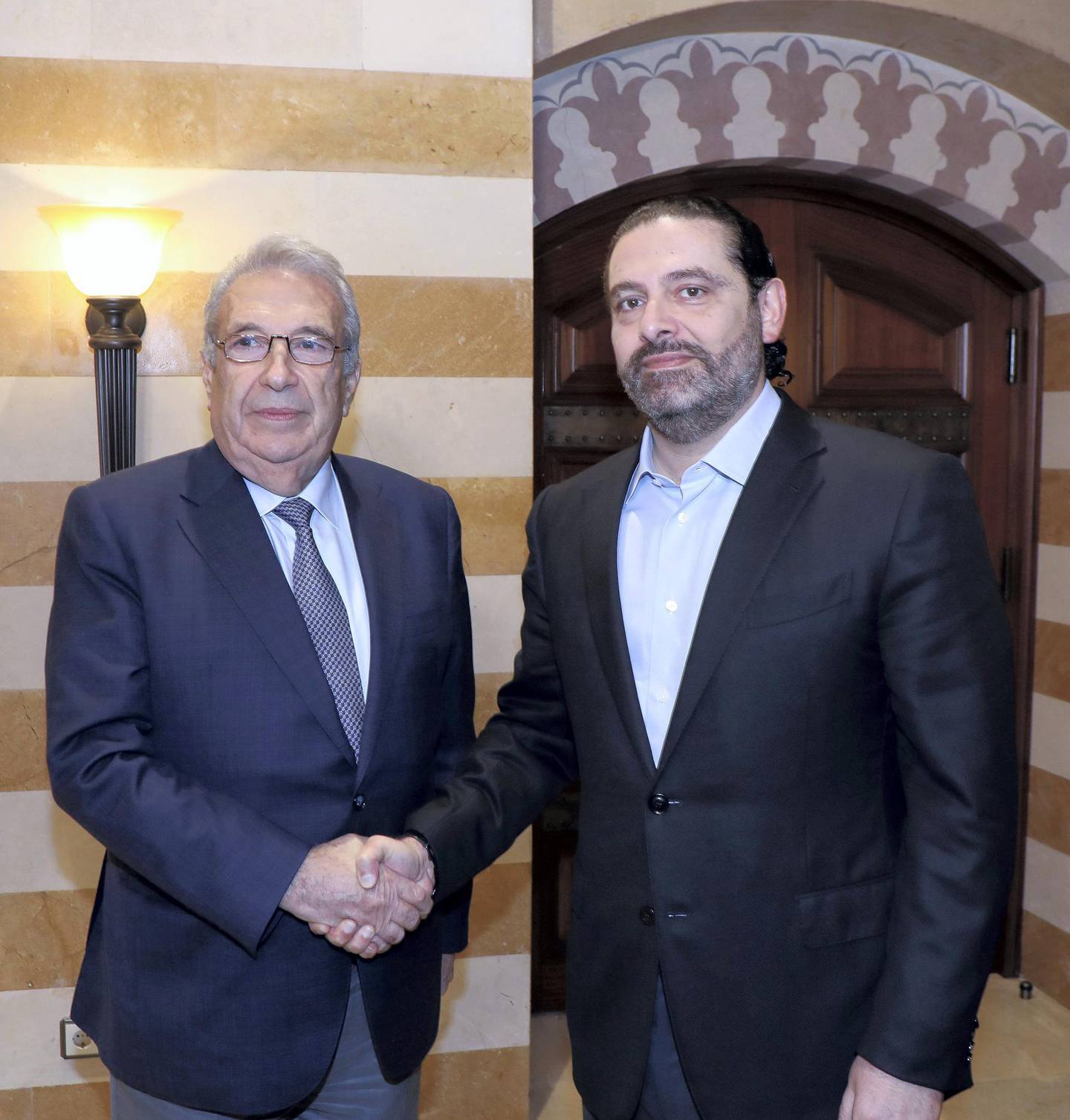 In this photo released by the Lebanese Government, Lebanon's outgoing Prime Minister Saad Hariri, right, shakes hand with Samir Khatib, the head of a major contracting and construction and once considered a favorite candidate for the post of Prime Minister, in Beirut, Lebanon, Sunday, Dec. 8, 2019. (Dalati Nohra via AP)