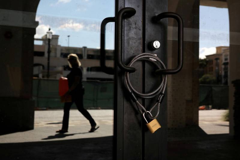 A restaurant is seen closed as a woman walks past at an empty commercial area after local authorities restricted the activities of restaurants, bars, gyms, movie theaters and other similar businesses in West Palm Beach, Florida, US. Reuters