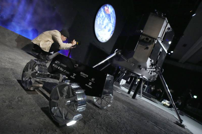 A photographer snaps models of the lander and lunar rover. AP