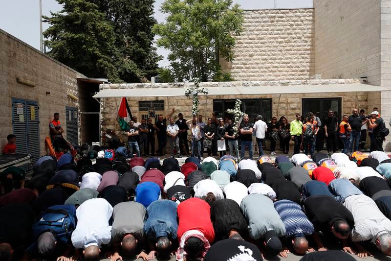 People pray as they gather at the St Joseph Hospital to pay tribute to Abu Akleh before her funeral. EPA
