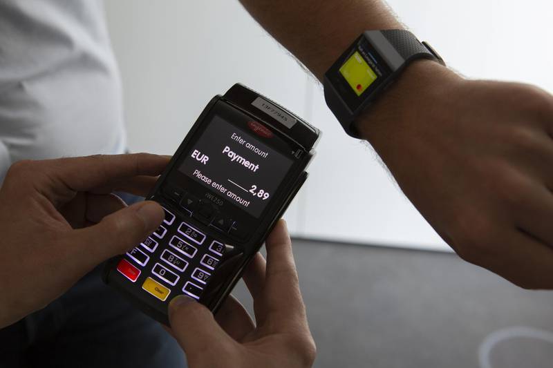 Employees hold a card payment terminal and display the Wirecard AG Boon app on a Fitbit Inc. smartwatch at the Wirecard headquarters in Munich, Germany, on Wednesday, Sept. 5, 2018. Commerzbank AG, part of the DAX Index stock gauge since its inception in 1988, will be replaced by fintech company Wirecard AG, index provider Deutsche Boerse AG said in a statement late on Wednesday. Photographer: Matthias Doering/Bloomberg