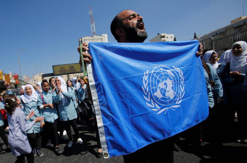A Palestinian demonstrator holds a United Nations' flag during a rally against a U.S. decision to cut funding to the United Nations Relief and Works Agency (UNRWA) and in support of president Mahmoud Abbas, in Bethlehem in the occupied West Bank September 26, 2018. REUTERS/Mussa Qawasma