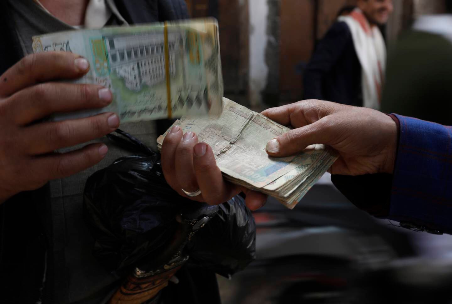 A customer holds Yemeni banknotes as he exchanges foreign currency amid a sharp devaluation of the Yemeni currency. EPA
