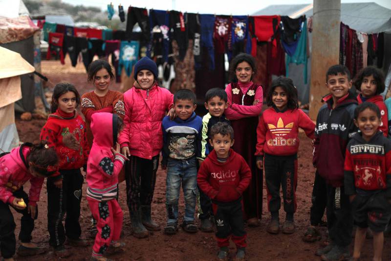 Children pose for a picture in a camp for displaced Syrians near the village of for the Kafr Uruq, in Syria's northern rebel-held Idlib province, on December 17, 2021.  AFP