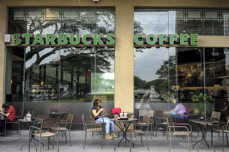 Customers sit inside and outside a Starbucks Corp. coffee shop at Parksons Mall in Kuching, Sarawak, Malaysia, on Wednesday, April 13, 2016. Separated from peninsular Malaysia by the South China Sea, Sarawak was the country's third-largest state or territory contributor to gross domestic product in 2015, accounting for an estimated 10.6 percent of output. Photographer: Sanjit Das/Bloomberg