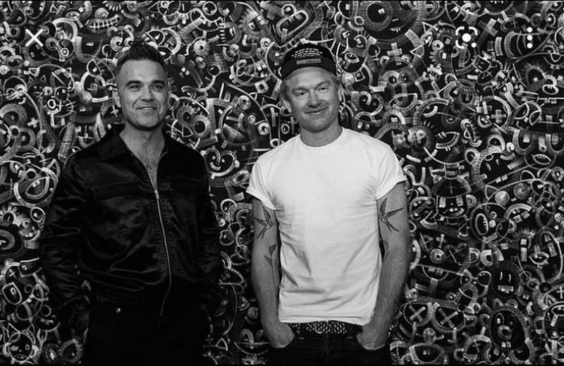 Robbie Williams and his creative partner Ed Godrich in front of one of their black and white paintings which are named after 80's girl's names. Photo: Twitter