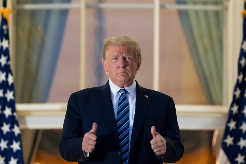President Donald Trump gives thumbs up as he stands on the Blue Room Balcony upon returning to the White House. AP Photo