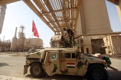 An Iraqi Shiite fighter cleans his weapon on his vehicle at the petrochemical plant in the town of Baiji, north of Tikrit, on October 16, 2015.