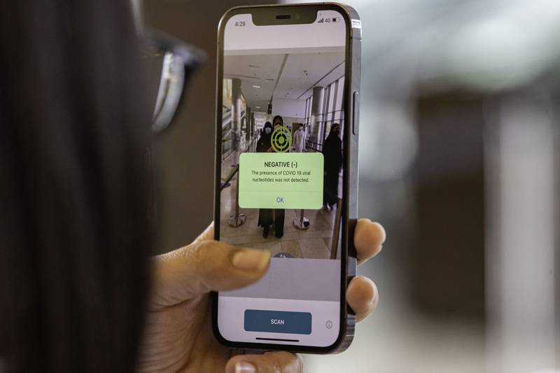 A smartphone with Covid-19 detection software shows a negative scan for a visitor at  Yas Mall in Abu Dhabi. The capital will use facial scanners to detect coronavirus infections at malls and airports after a trial of 20,000 people showed 'a high degree of effectiveness'.