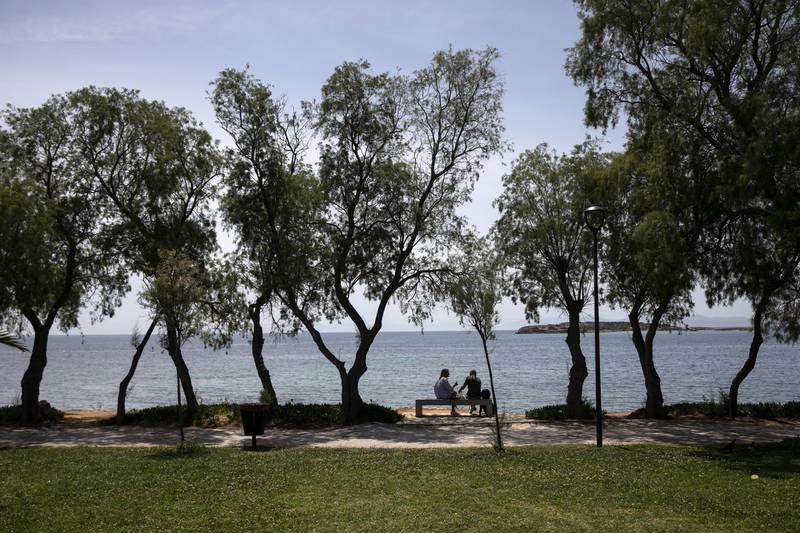 Visitors take in the scenery from the beachside at Voula suburb, south of Athens. Photographer: Yorgos Karahalis/Bloomberg