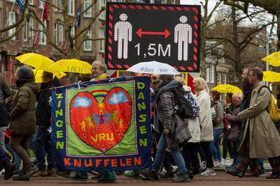 Protesters pass a digital billboard urging people to respect social distancing guidelines during a demonstration against coronavirus restrictions in Amsterdam, the Netherlands. AP Photo