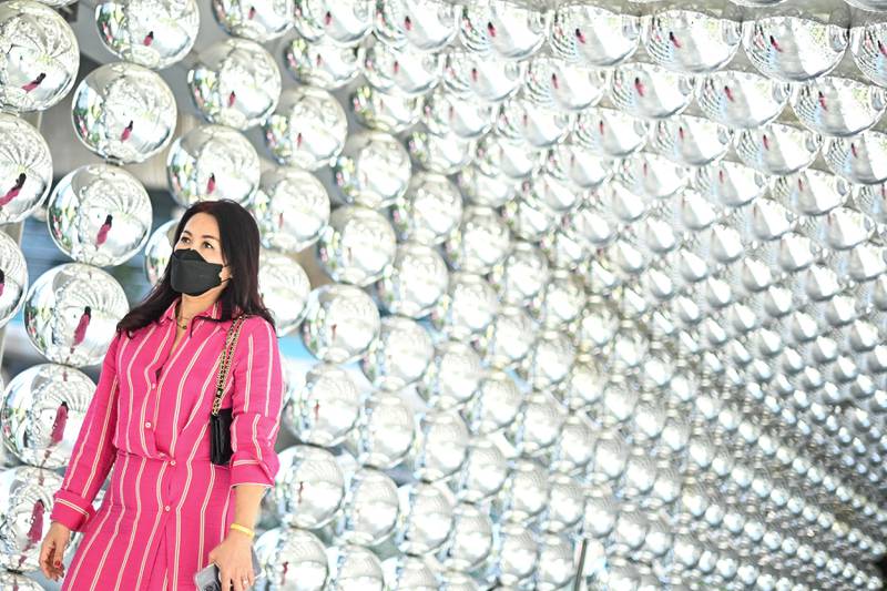 A woman walks past a decoration made of reflective balls outside a shopping mall in Bangkok. AFP