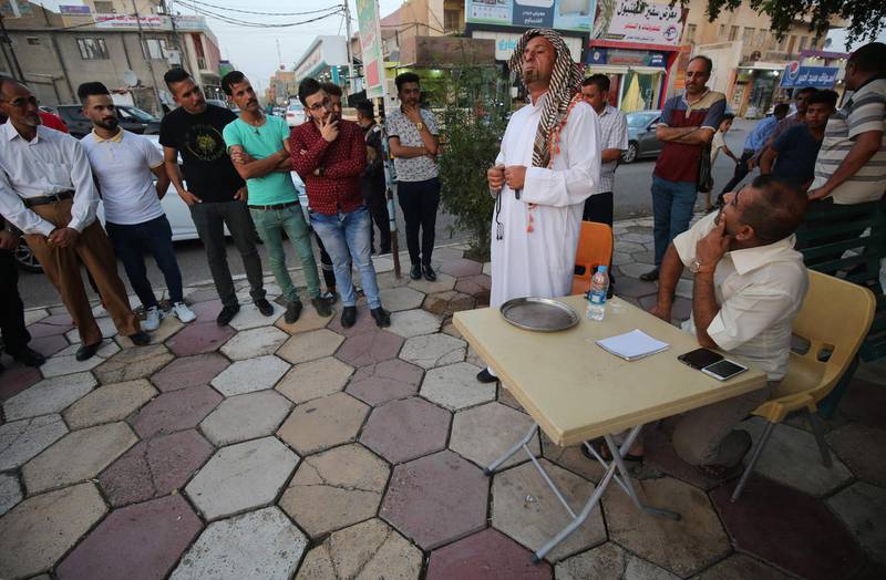 An Iraqi man performs a theatrical skit on the Corniche Street in the southern Iraqi city of Kut on July 6, 2018.  On a small strip of pavement in the southern Iraqi city of Kut, a gaggle of amateur comedians pulls in the crowds every Friday -- drawing chuckles, smiles and knowing nods. / AFP / AHMAD AL-RUBAYE
