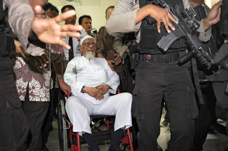 (FILES) This file photo taken on February 29, 2012 shows Indonesian cleric Abu Bakar Bashir (C) escorted by elite Indonesian police commandos upon his arrival at hospital in a wheelchair to undergo cataract surgery in Jakarta. Bashir, a radical Indonesian cleric linked to the deadly Bali bombings, will be released from prison this week, authorities said on January 4, 2021, after an earlier bid to free him early was axed following a public uproar. / AFP / Romeo GACAD
