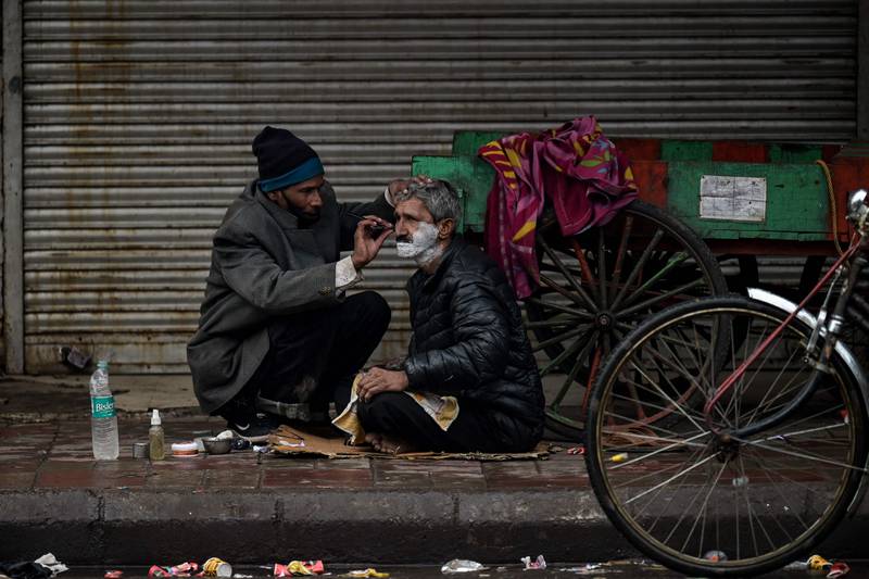 A migrant labourer has a shave in the old quarters of Delhi’s walled city. The Indian capital has imposed a  state-wide weekend curfew to curb cases of Covid-19. AFP
