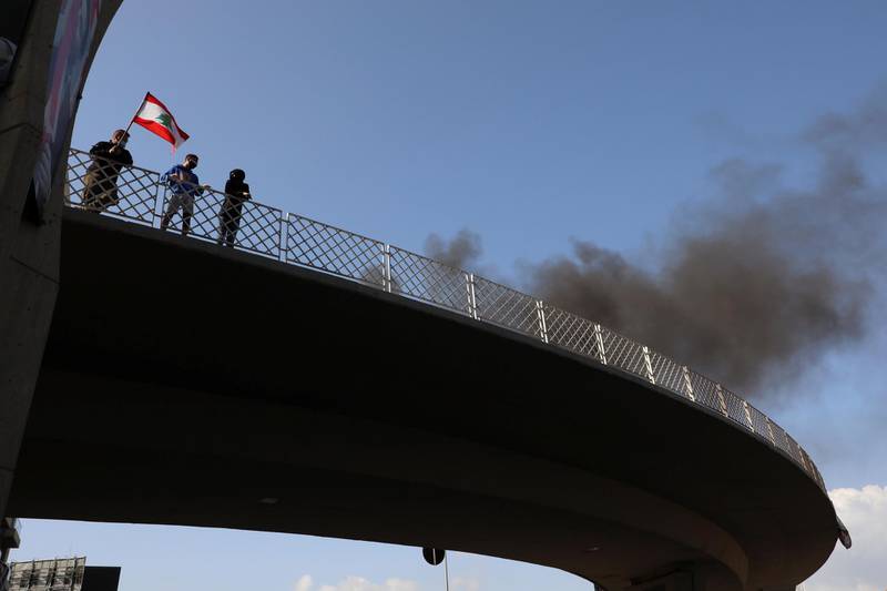 Demonstrators stand on a bridge as smoke rises from tyres set on fire in Jal el-Dib. Reuters