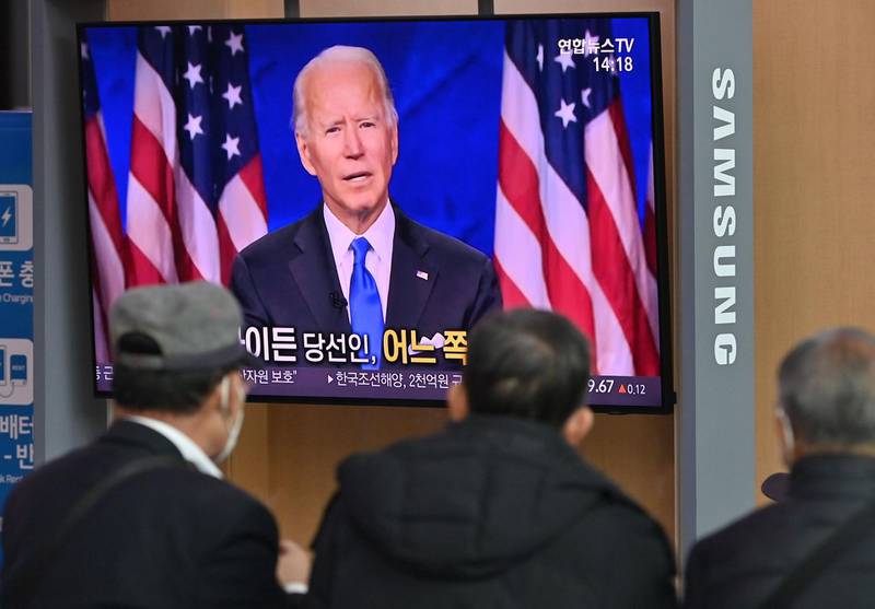 People watch a television news programme reporting on the US presidential election showing an image of US President-elect Joe Biden, at a railway station in Seoul on November 9, 2020. / AFP / Jung Yeon-je
