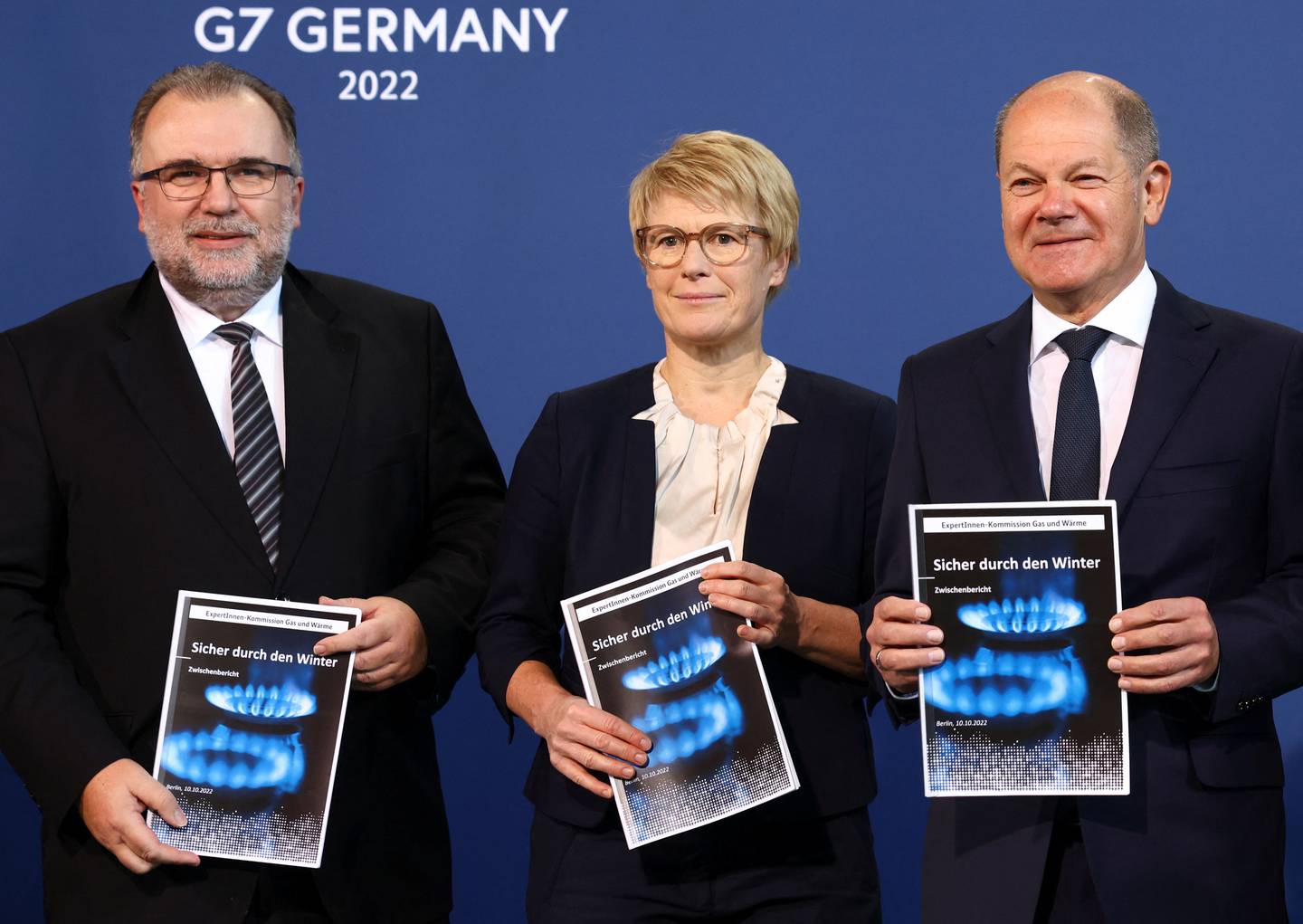 German Chancellor Olaf Scholz, right, holds up a written proposal to subsidise energy prices. Reuters 