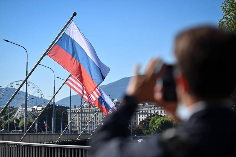 A man takes a picture of Russian and US flags on the Mont-Blanc bridge in Geneva. AFP