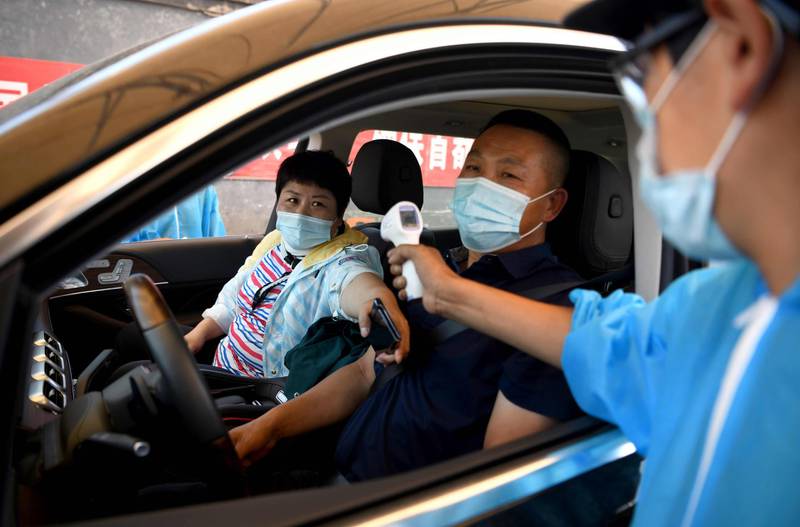 A security personnel wearing a protective suit checks the temperature of people entering the Xinfadi market in Beijing.  AFP