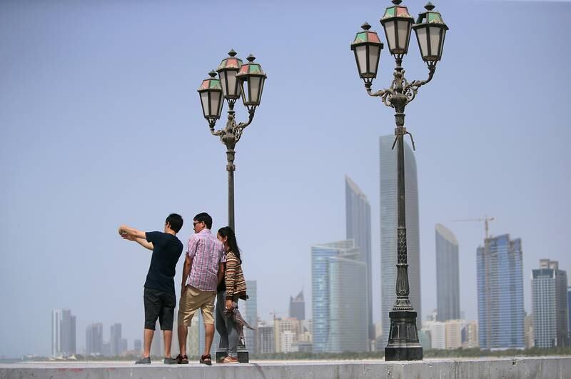 ABU DHABI - UNITED ARAB EMIRATES - 29JULY2016 - Visitors take quick selfies and photographs with Abu Dhabi skyline in the backdrop as the temperature scales 41 degree celsius with humidity showing 41 percentage at the breakwaters on the Corniche. Ravindranath K / The National (for Standalone) *** Local Caption ***  RK2907-STANDALONE01.jpg
