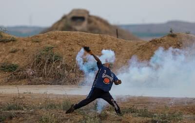 A Palestinian protester throws back an Israeli tear gas canister on the eastern border of the Gaza Strip. EPA