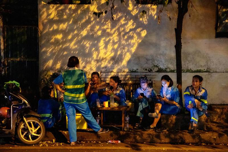 Workers sit on stools along a street in Hanoi, Vietnam. Bloomberg