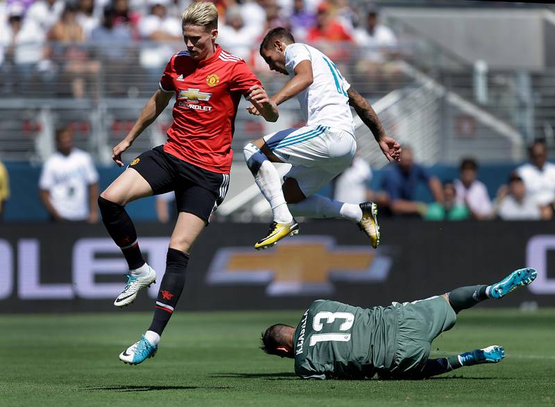 Manchester United's Scott McTominay, left, and Real Madrid's Fabio Coentrao jump over Real Madrid goalie Francisco Casilla. Ben Margot / AP Photo