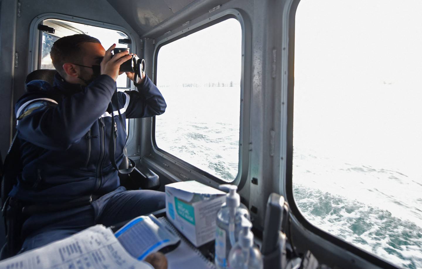 A French Maritime Gendarme looks through a pair of binoculars as he and his colleagues search for migrants trying to cross the Channel. AFP