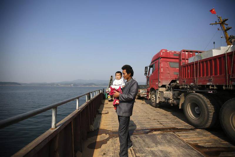 A Chinese man holds his child on a ferry barge on Danjiangkou reservoir, part of the central route of the South-to-North Water Transfer project in Xichuan county, Henan Province, China. How Hwee Young/EPA