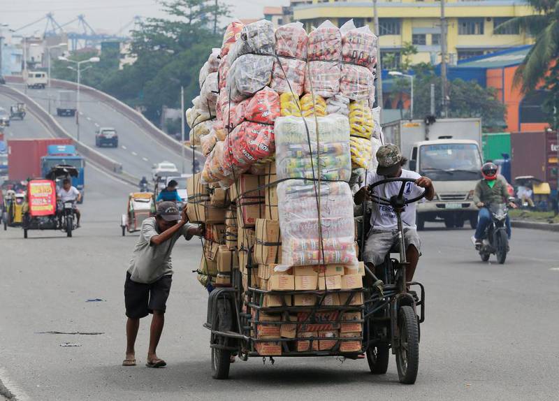 A worker helps his colleague push a bicycle filled with boxes of biscuits in Manila. Romeo Ranoco / Reuters